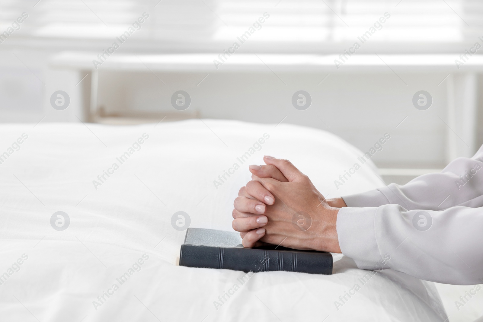 Religious woman with Bible praying in bedroom, closeup Photo of Religious woman with Bible praying in bedroom, closeup
