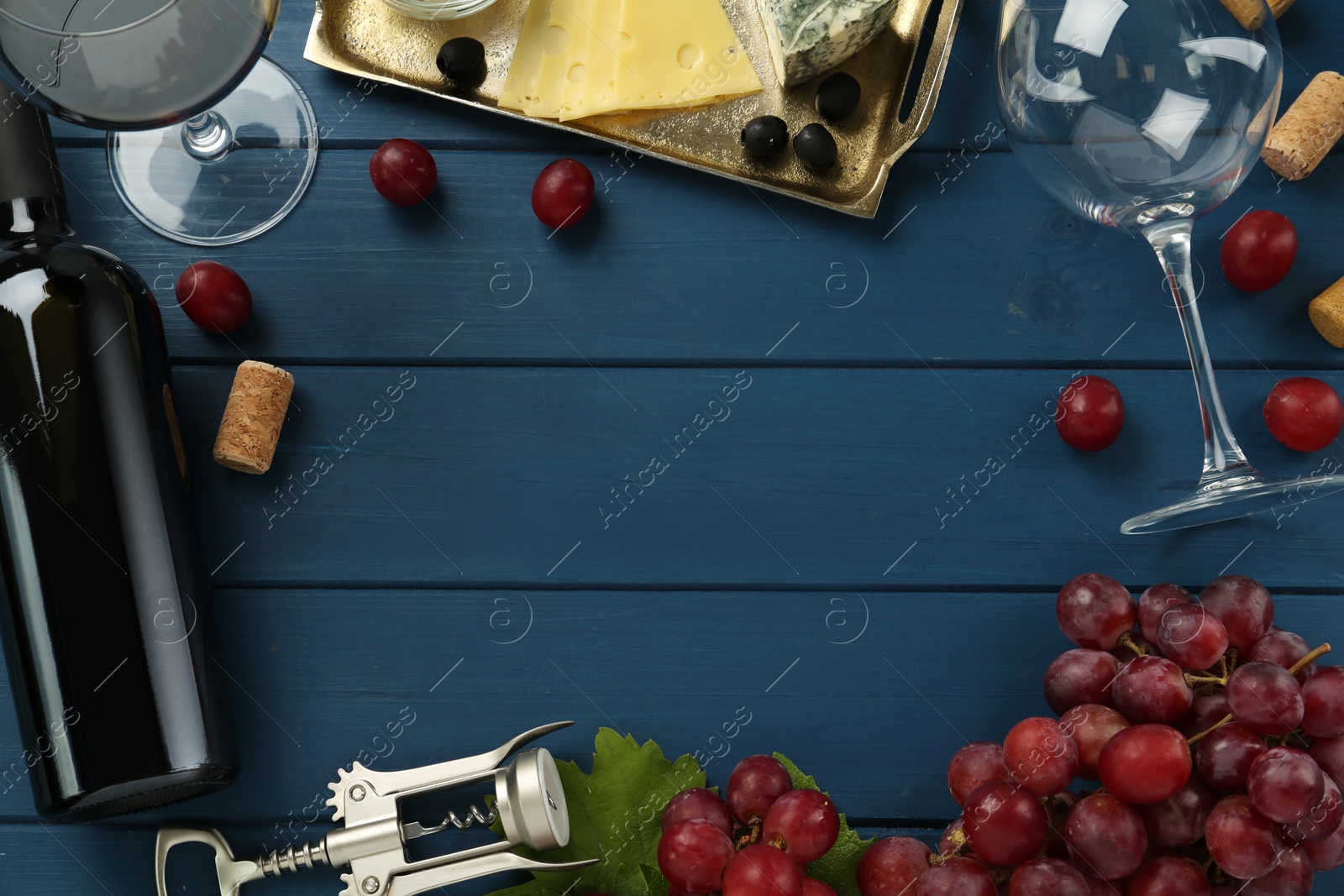 Flat lay composition with tasty red wine and grapes on blue wooden table, space for text Photo of Flat lay composition with tasty red wine and grapes on blue wooden table, space for text