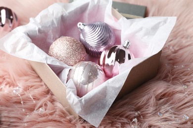 Photo of Beautiful Christmas baubles in box on pink faux fur