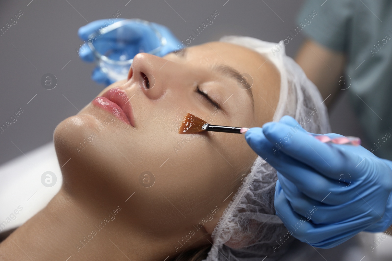Cosmetologist applying chemical peel product on client's face in salon Photo of Cosmetologist applying chemical peel product on client's face in salon