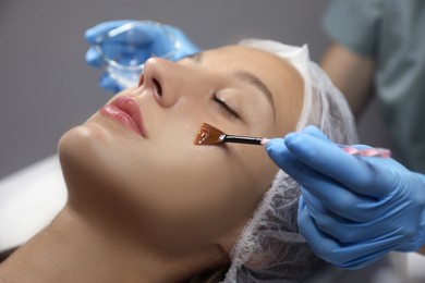Cosmetologist applying chemical peel product on client's face in salon Photo of Cosmetologist applying chemical peel product on client's face in salon