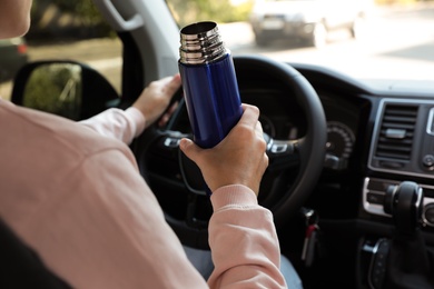 Woman with thermos driving car, closeup view Photo of Woman with thermos driving car, closeup view