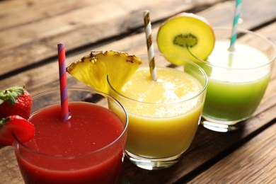 Delicious colorful juices in glasses on wooden table, closeup Photo of Delicious colorful juices in glasses on wooden table, closeup
