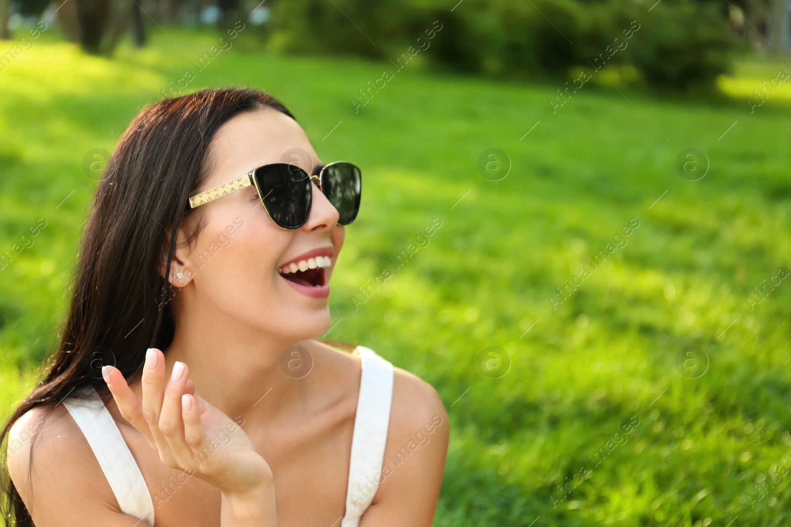 Beautiful young woman wearing stylish sunglasses in park. Space for text Photo of Beautiful young woman wearing stylish sunglasses in park. Space for text