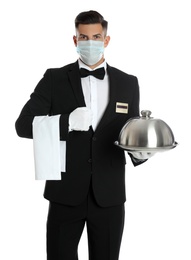 Waiter in medical face mask holding tray with lid on white background Photo of Waiter in medical face mask holding tray with lid on white background