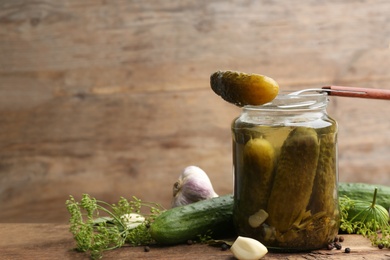 Glass jar of pickled cucumbers and ingredients on wooden table. Space for text Photo of Glass jar of pickled cucumbers and ingredients on wooden table. Space for text