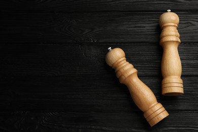 Salt and pepper shakers on black wooden table, flat lay. Space for text Photo of Salt and pepper shakers on black wooden table, flat lay. Space for text