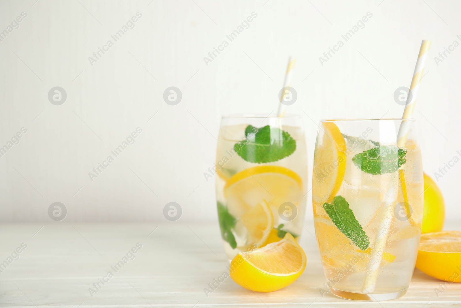 Photo of Cool freshly made lemonade in glasses on white wooden table. Space for text