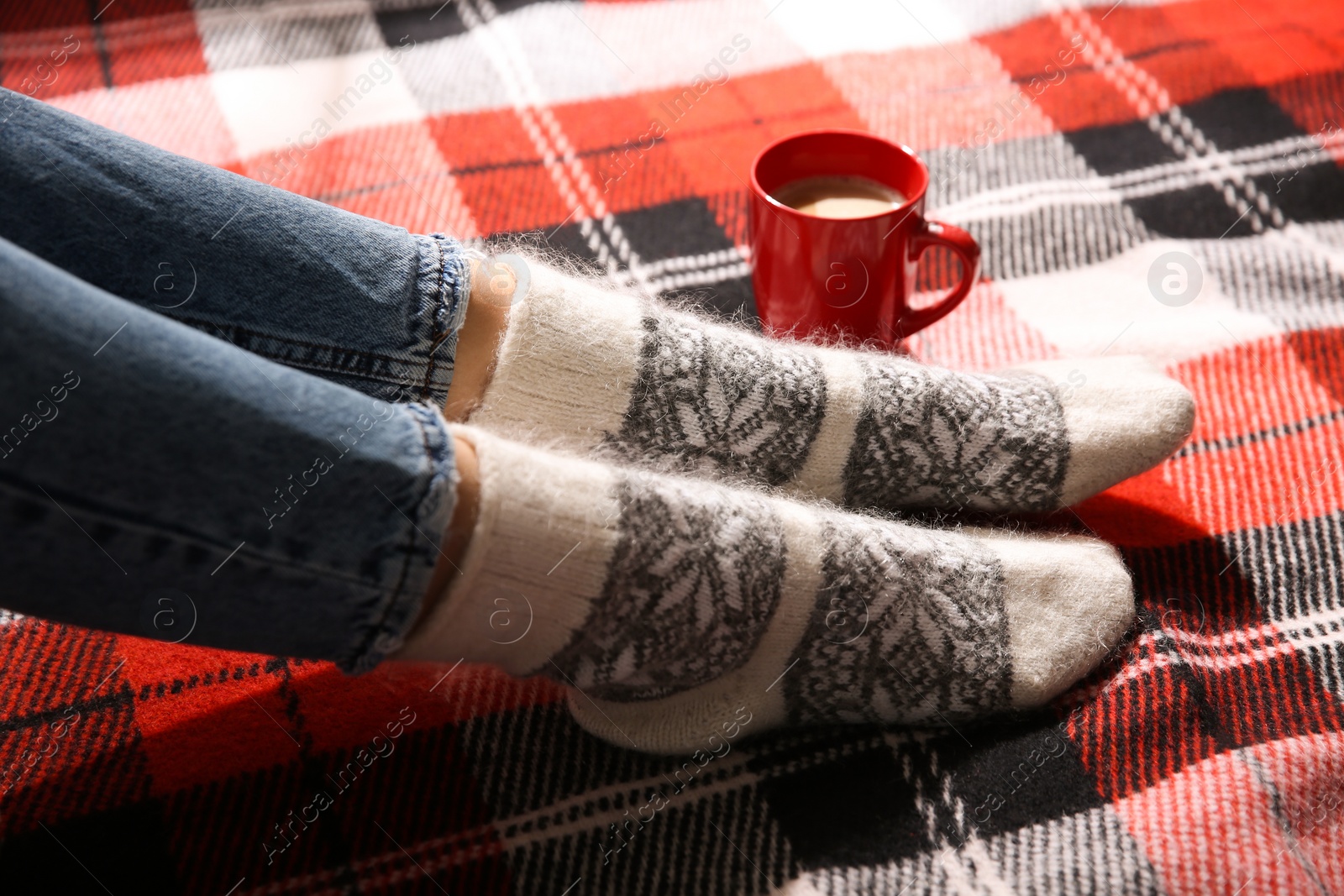 Photo of Woman relaxing on checkered plaid, closeup. Cozy season
