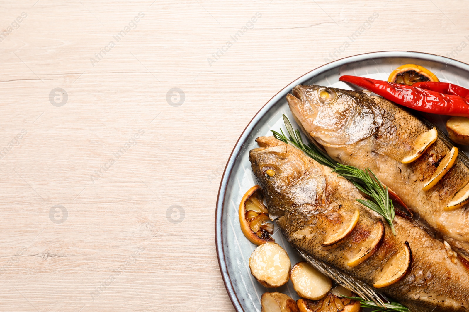 Tasty homemade roasted perches with garnish on wooden table, top view and space for text. River fish Photo of Tasty homemade roasted perches with garnish on wooden table, top view and space for text. River fish