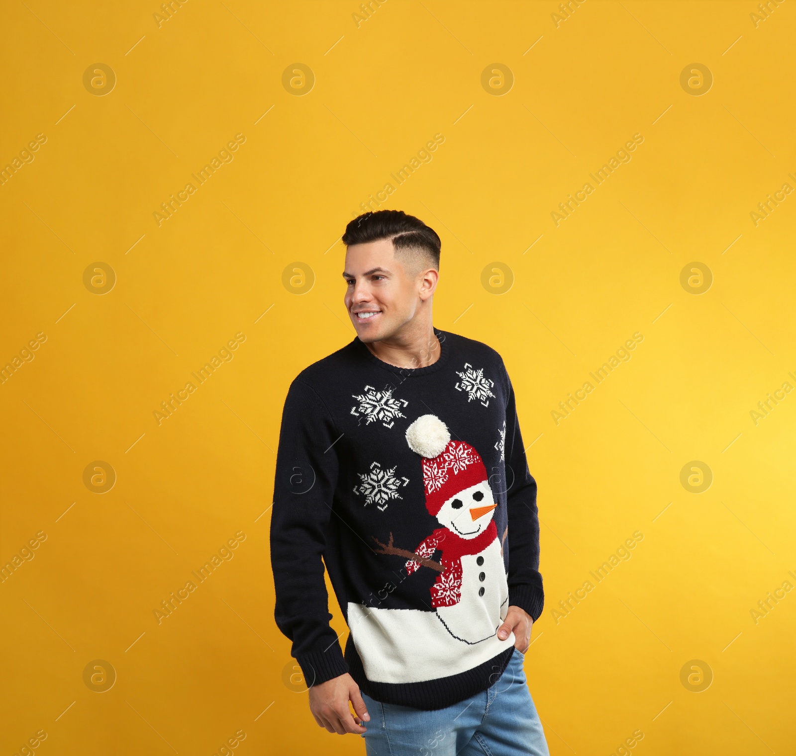 Handsome man in Christmas sweater on yellow background Photo of Handsome man in Christmas sweater on yellow background