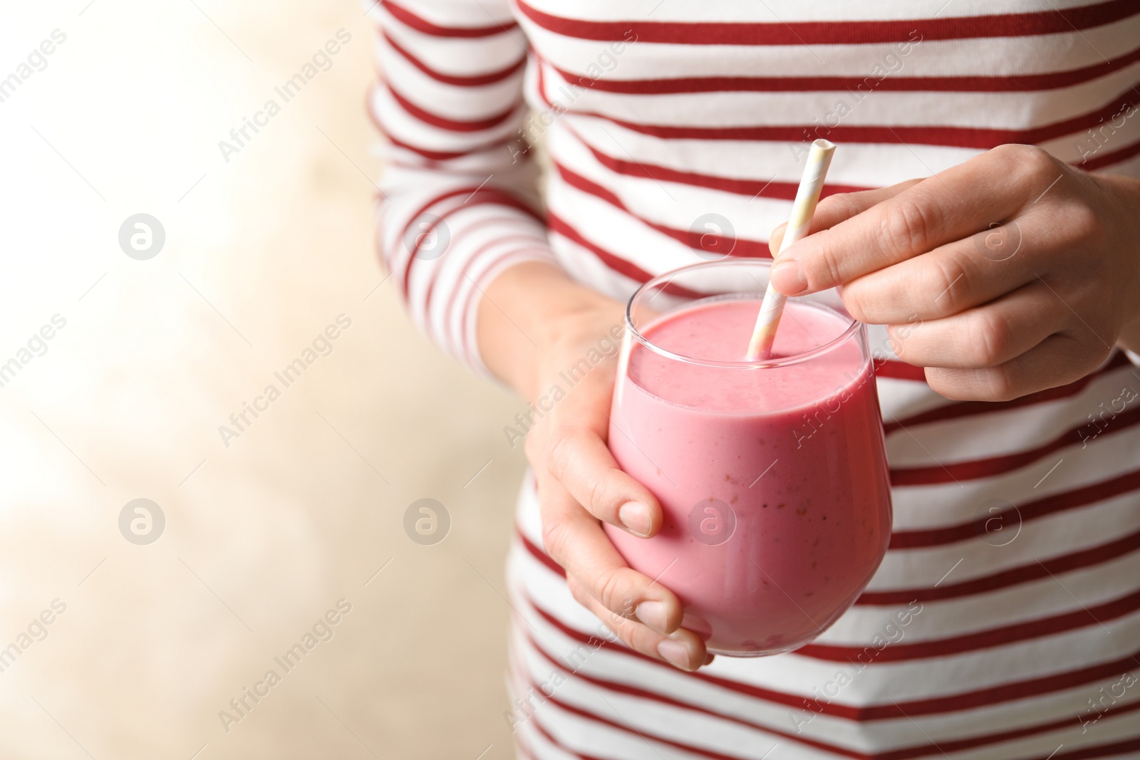 Woman with glass of tasty smoothie on beige background, closeup Image of Woman with glass of tasty smoothie on beige background, closeup