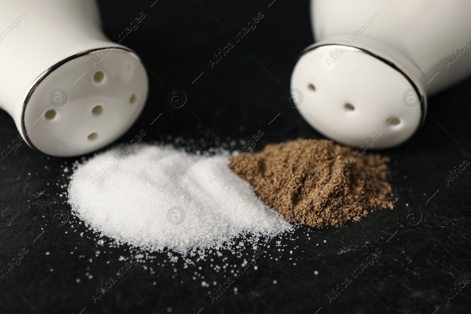 White ceramic salt and pepper shakers on black table, closeup Photo of White ceramic salt and pepper shakers on black table, closeup