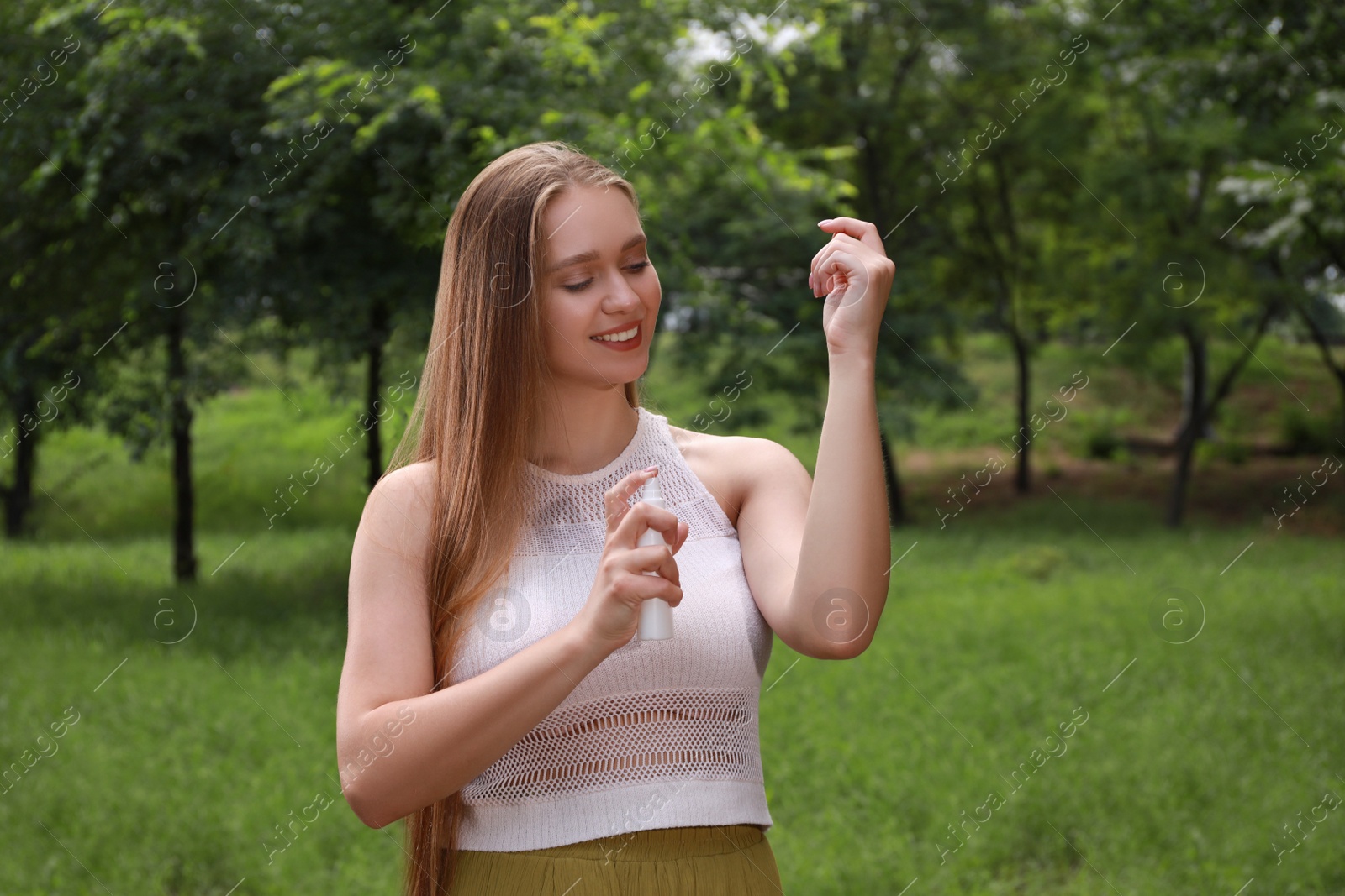 Woman applying insect repellent onto arm in park. Tick bites prevention Photo of Woman applying insect repellent onto arm in park. Tick bites prevention