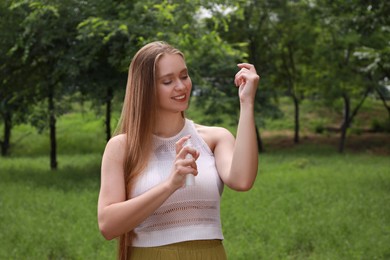 Woman applying insect repellent onto arm in park. Tick bites prevention Photo of Woman applying insect repellent onto arm in park. Tick bites prevention