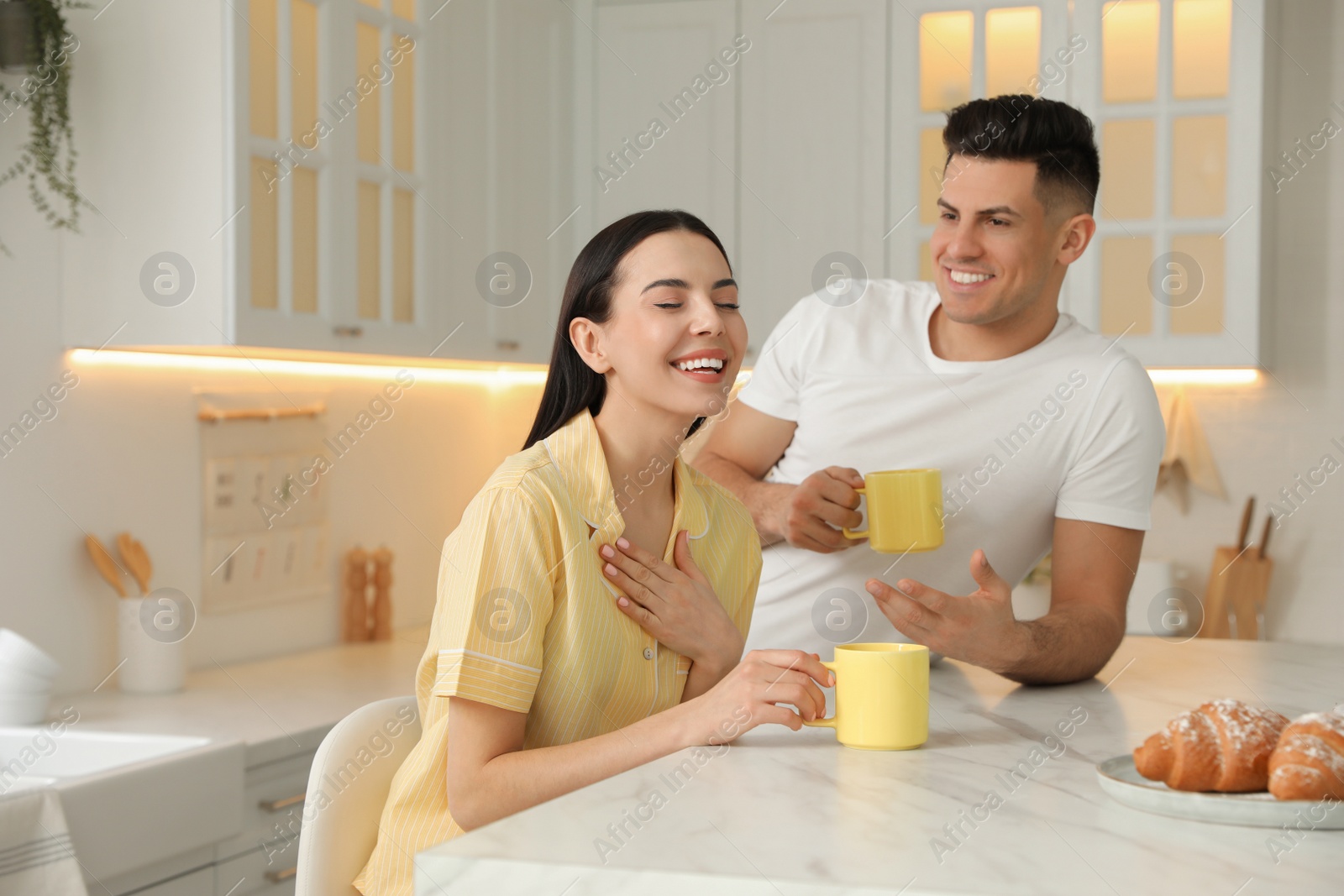 Happy couple wearing pyjamas during breakfast at table in kitchen Photo of Happy couple wearing pyjamas during breakfast at table in kitchen