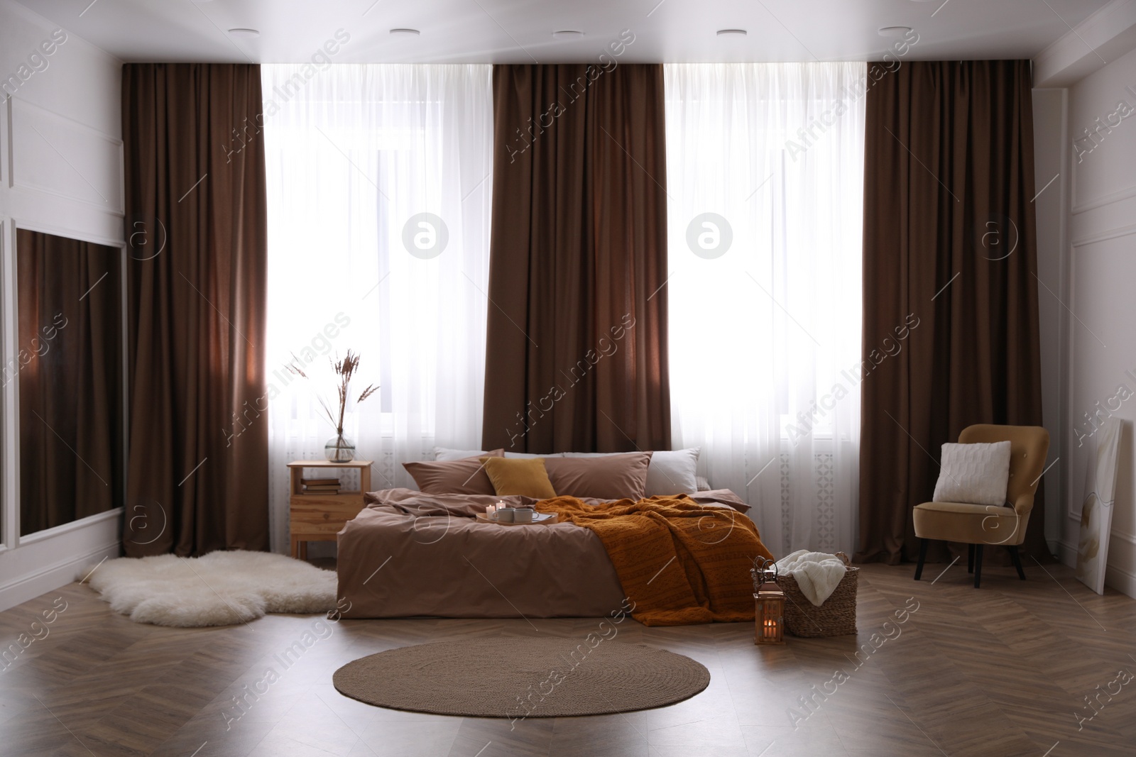 Bed with brown linens in stylish room interior Photo of Bed with brown linens in stylish room interior