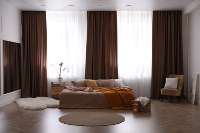 Bed with brown linens in stylish room interior Photo of Bed with brown linens in stylish room interior