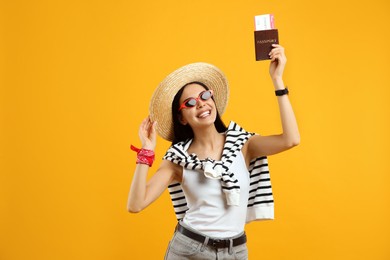 Happy female tourist with ticket and passport on yellow background Photo of Happy female tourist with ticket and passport on yellow background