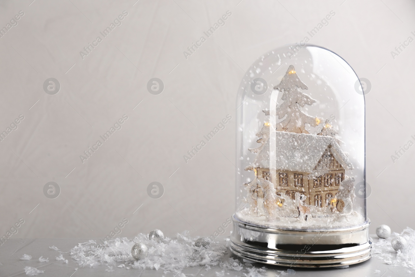 Beautiful snow globe on grey table against light background, space for text Photo of Beautiful snow globe on grey table against light background, space for text