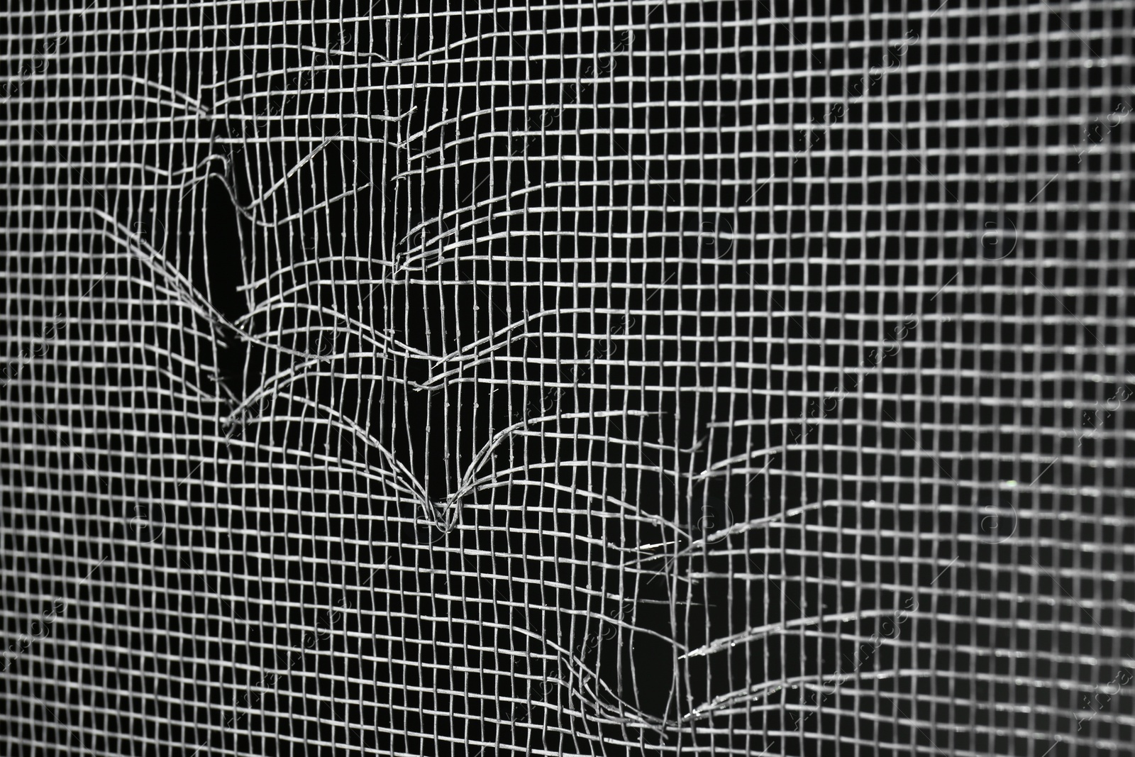 Torn window screen against black background, closeup Photo of Torn window screen against black background, closeup