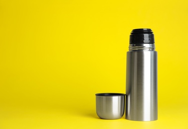 Stylish thermo bottle on yellow background, space for text Photo of Stylish thermo bottle on yellow background, space for text