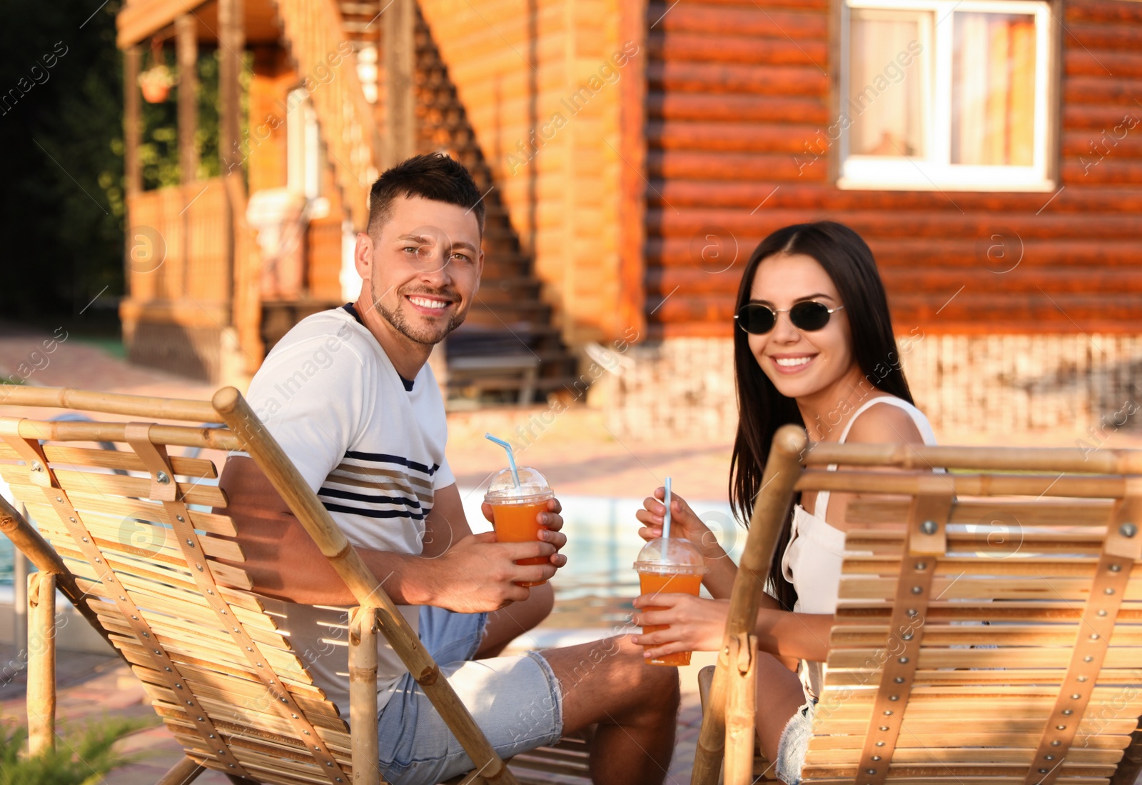Happy couple with cups of refreshing drink resting in deck chairs outdoors Image of Happy couple with cups of refreshing drink resting in deck chairs outdoors