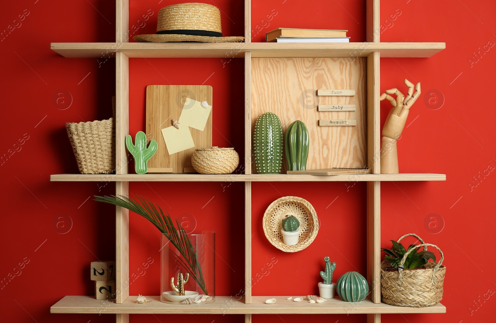 Stylish wooden shelves with decorative elements on red wall Photo of Stylish wooden shelves with decorative elements on red wall