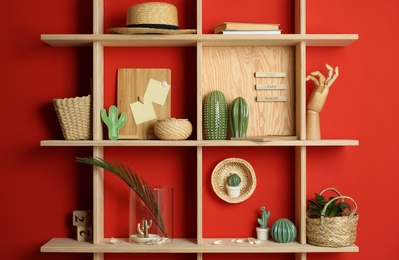 Stylish wooden shelves with decorative elements on red wall Photo of Stylish wooden shelves with decorative elements on red wall