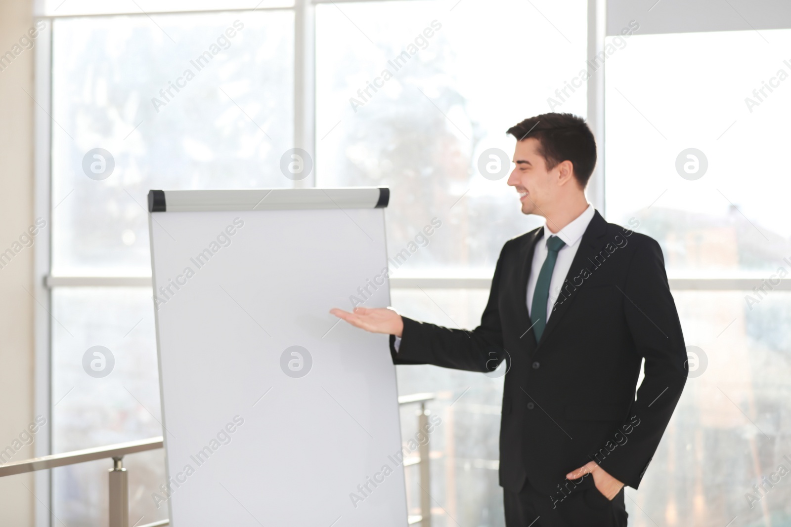 Business trainer giving presentation on flip chart board indoors Photo of Business trainer giving presentation on flip chart board indoors