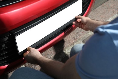 Man installing vehicle registration plate outdoors, closeup. Mockup for design Photo of Man installing vehicle registration plate outdoors, closeup. Mockup for design