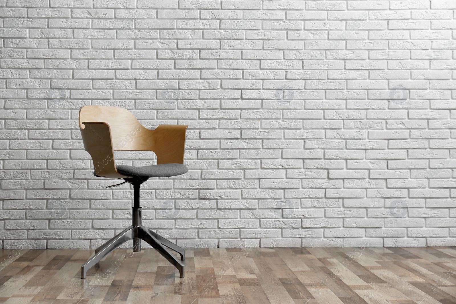 Comfortable office chair near white brick wall indoors. Space for text Photo of Comfortable office chair near white brick wall indoors. Space for text