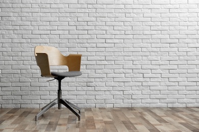 Comfortable office chair near white brick wall indoors. Space for text Photo of Comfortable office chair near white brick wall indoors. Space for text