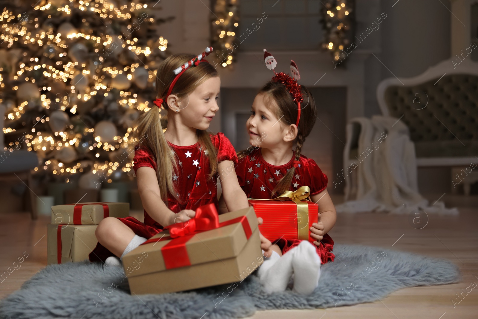 Cute little children with Christmas gifts in living room Photo of Cute little children with Christmas gifts in living room