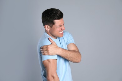 Man suffering from shoulder pain on grey background Photo of Man suffering from shoulder pain on grey background