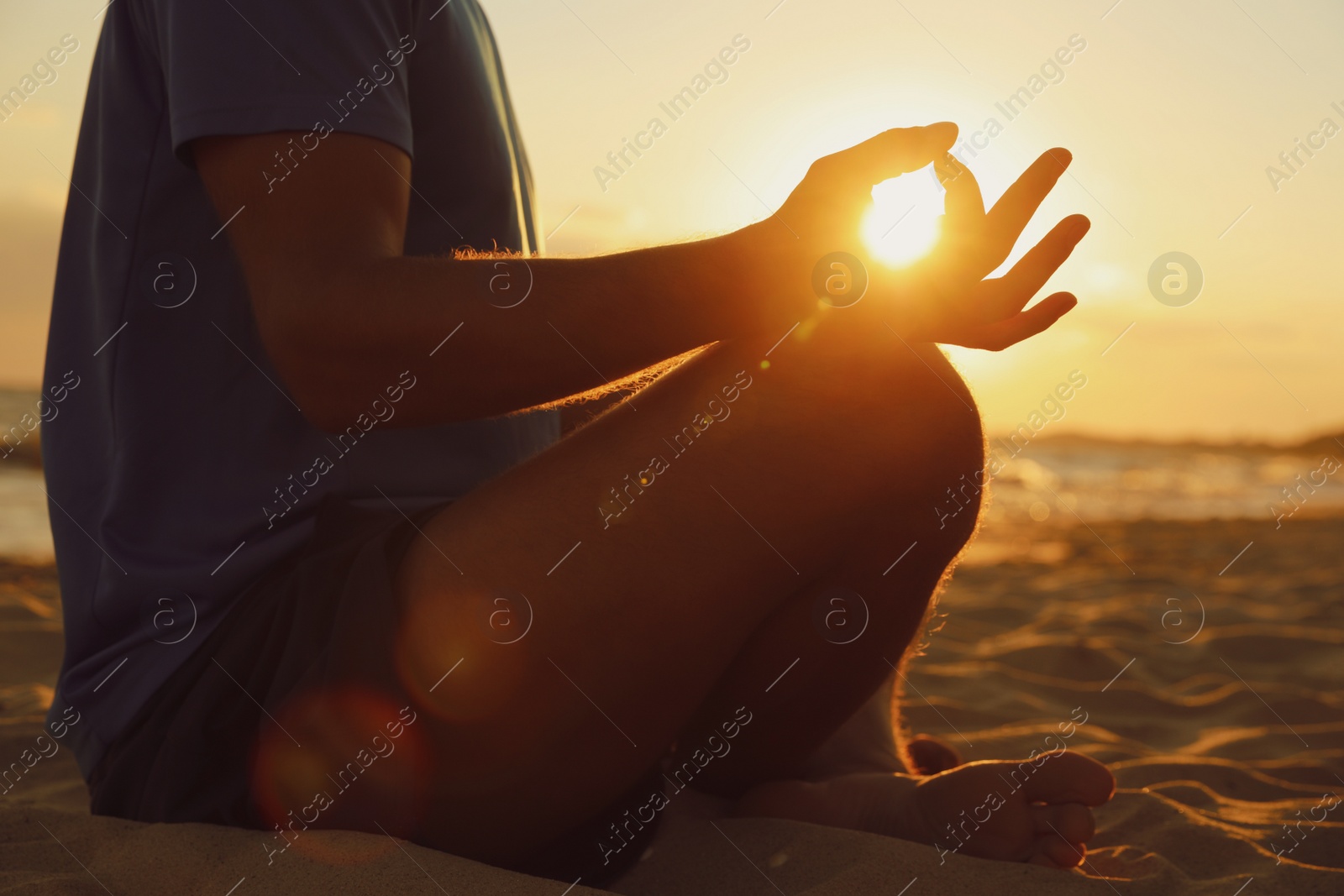Man meditating on sandy beach at sunset, closeup Photo of Man meditating on sandy beach at sunset, closeup