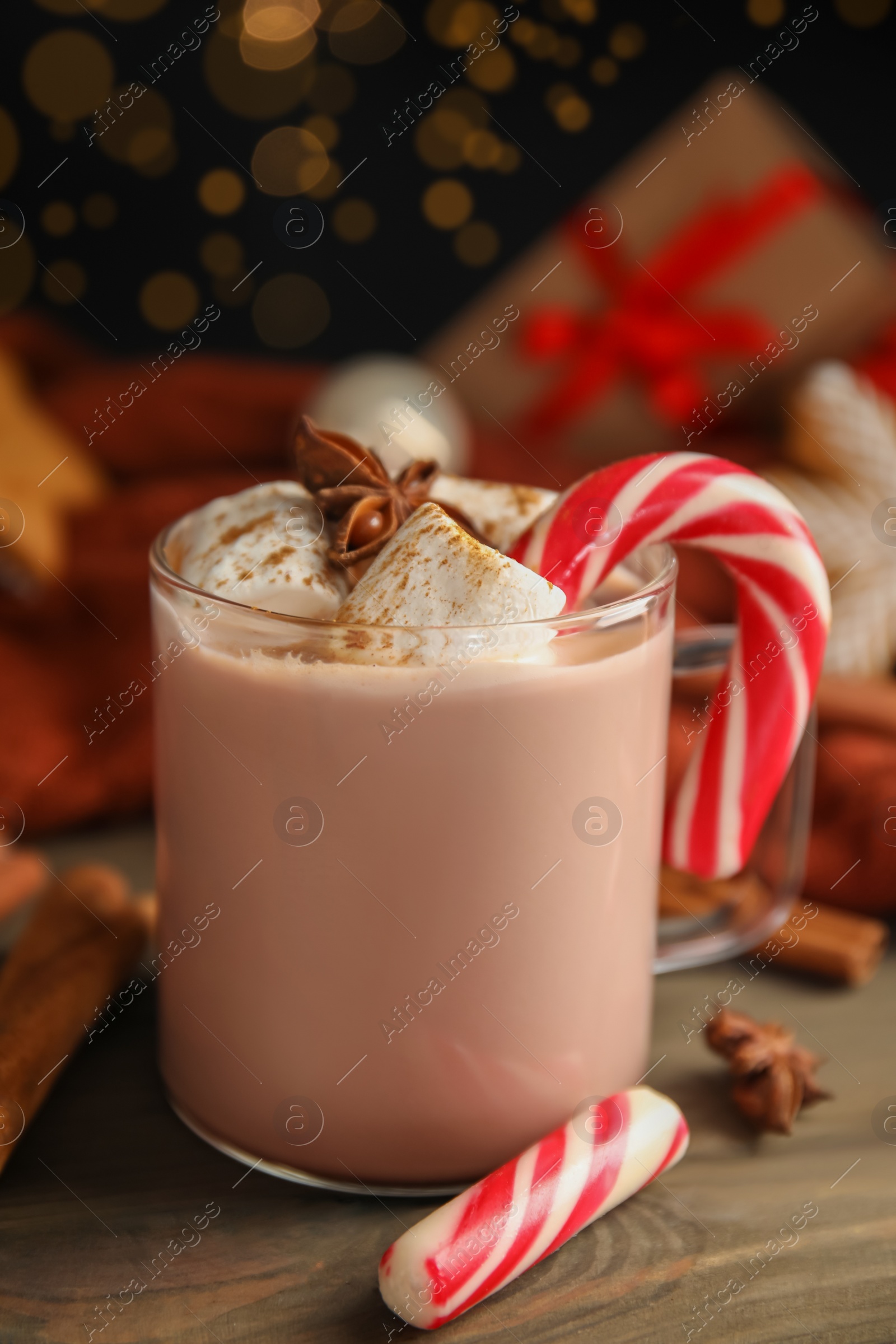 Glass cup of tasty cocoa with marshmallows and Christmas candy cane on wooden table Photo of Glass cup of tasty cocoa with marshmallows and Christmas candy cane on wooden table