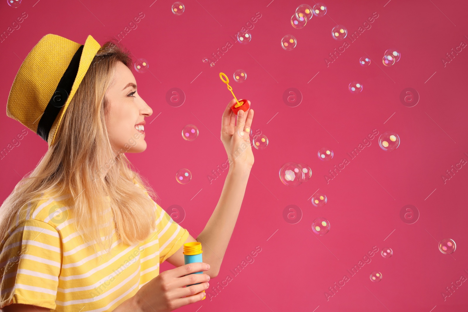 Young woman blowing soap bubbles on pink background, space for text Photo of Young woman blowing soap bubbles on pink background, space for text