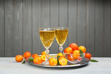 Delicious plum liquor and ripe fruits on table against grey background. Homemade strong alcoholic beverage Photo of Delicious plum liquor and ripe fruits on table against grey background. Homemade strong alcoholic beverage