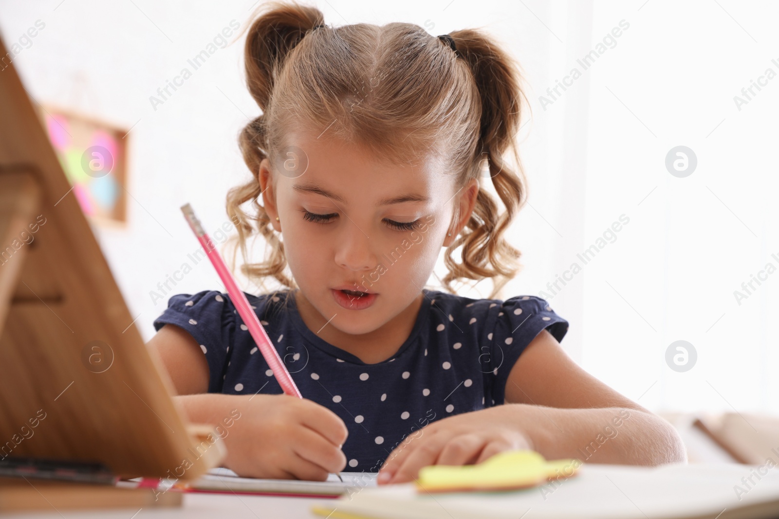 Cute little girl doing homework at table Photo of Cute little girl doing homework at table