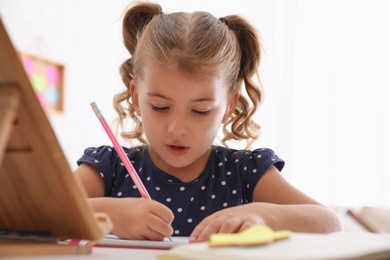 Cute little girl doing homework at table Photo of Cute little girl doing homework at table