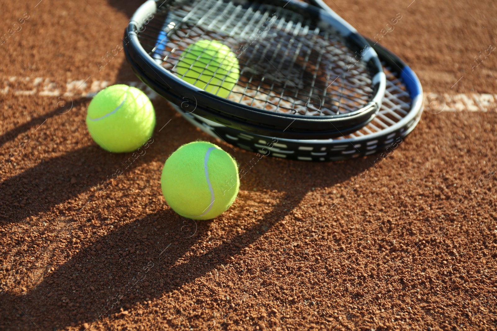 Tennis balls and rackets on clay court Photo of Tennis balls and rackets on clay court