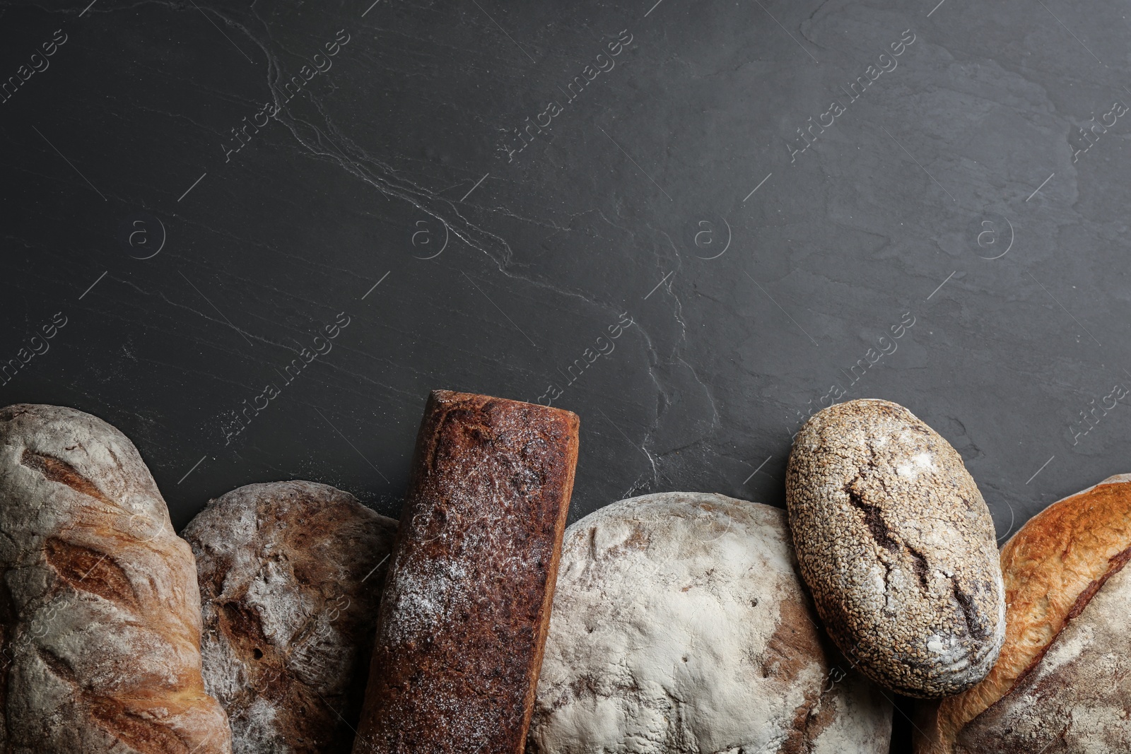 Different kinds of delicious bread on black table, flat lay. Space for text Photo of Different kinds of delicious bread on black table, flat lay. Space for text