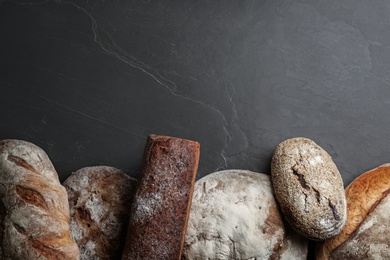 Different kinds of delicious bread on black table, flat lay. Space for text Photo of Different kinds of delicious bread on black table, flat lay. Space for text