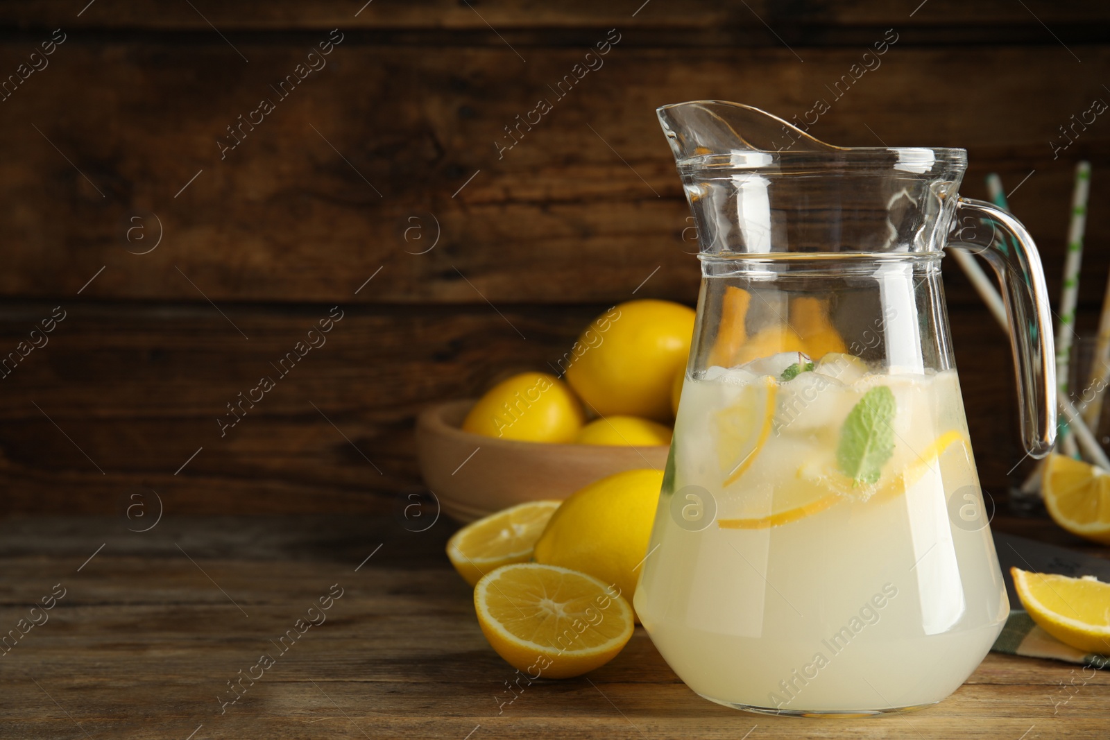 Cool freshly made lemonade in glass pitcher on wooden table. Space for text Photo of Cool freshly made lemonade in glass pitcher on wooden table. Space for text