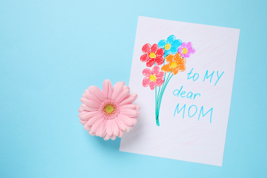Handmade greeting card for Mother's day and flower on light blue background, flat lay Photo of Handmade greeting card for Mother's day and flower on light blue background, flat lay