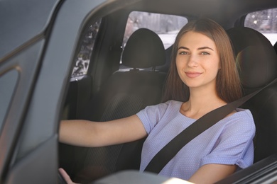 Young woman with fastened safety belt on driver's seat in car Photo of Young woman with fastened safety belt on driver's seat in car