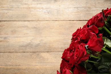 Luxury bouquet of fresh red roses on wooden table, top view. Space for text Photo of Luxury bouquet of fresh red roses on wooden table, top view. Space for text
