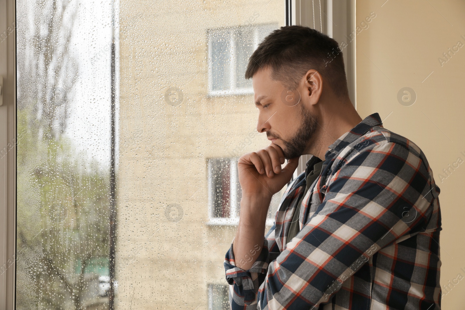 Depressed man near window at home. Space for text Photo of Depressed man near window at home. Space for text