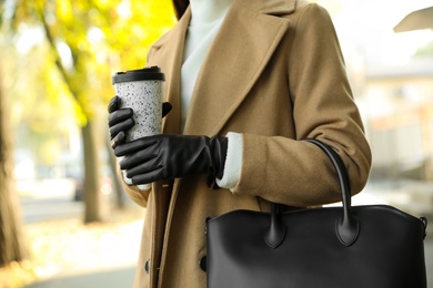 Woman with stylish leather gloves and cup of coffee on city street, closeup Photo of Woman with stylish leather gloves and cup of coffee on city street, closeup